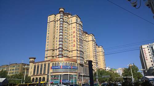 high rise low-angle photography of beige concrete building under blue sky town
